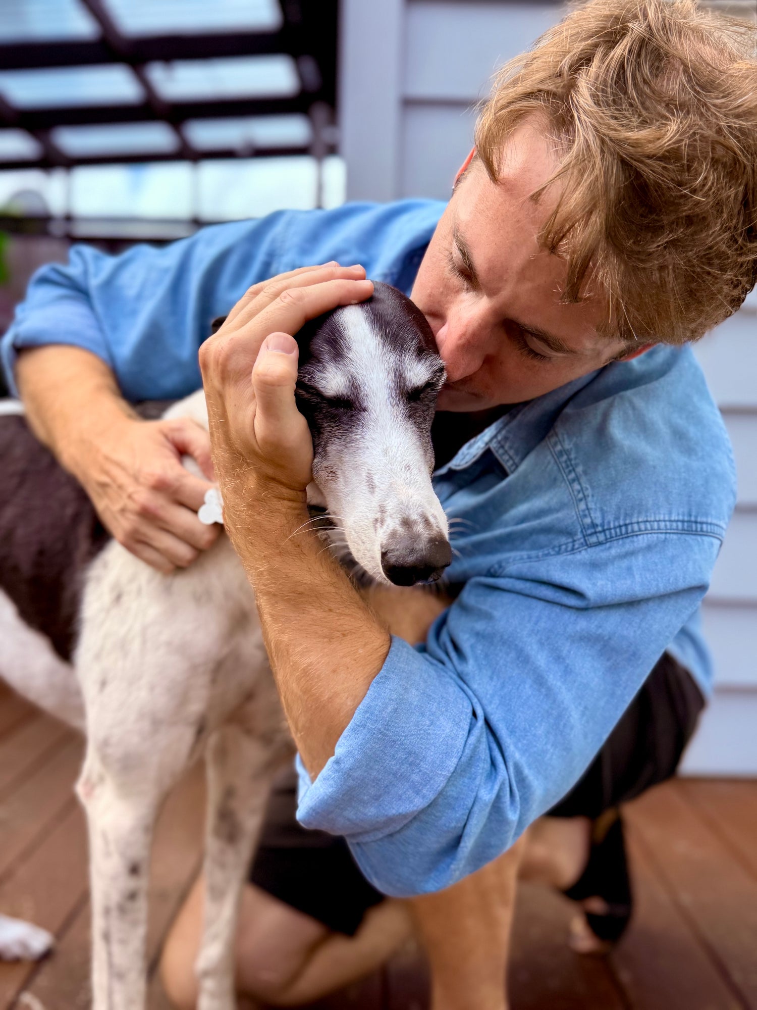 Dr. Ferg's in a blue shirt petting Ace the dog on a wooden deck. Buy the best dog supplements online for dogs in the US. Premium vet-formulated supplements by a family business. 